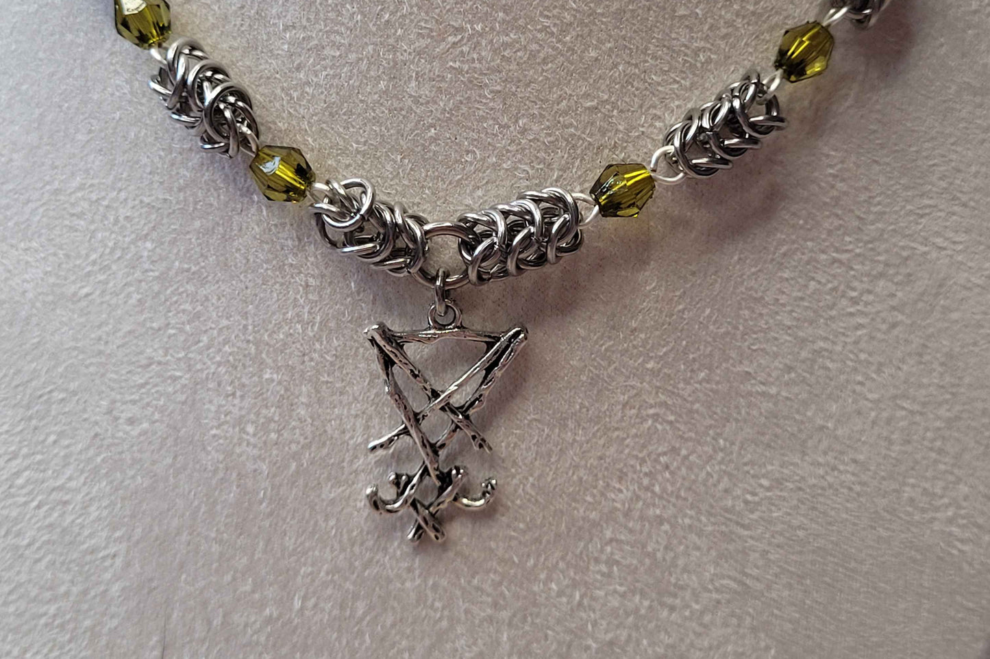 Necklace with silver chain, green beads, and a small silver pendant on a light gray background